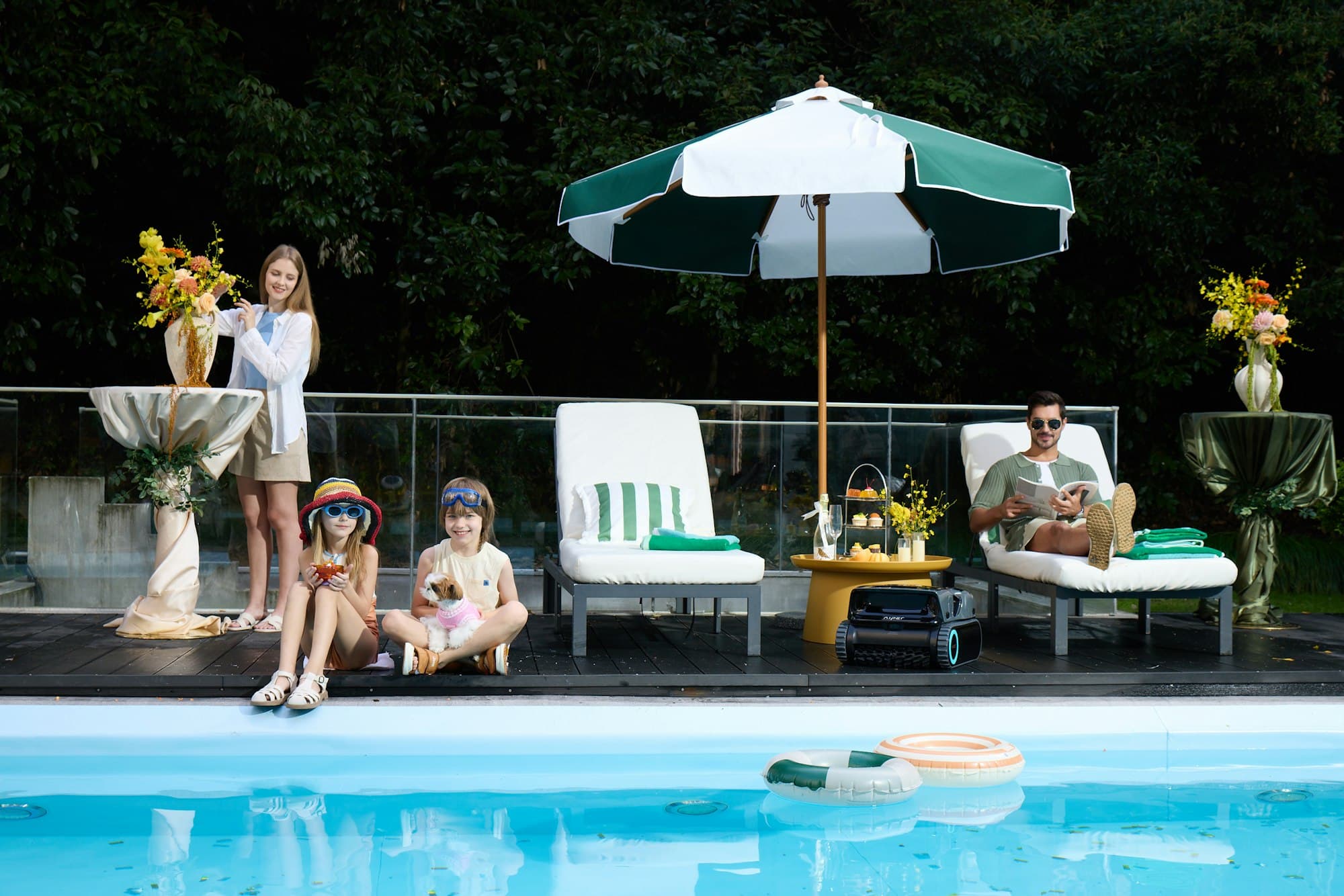 A family relaxing beside a sunny pool under a striped umbrella