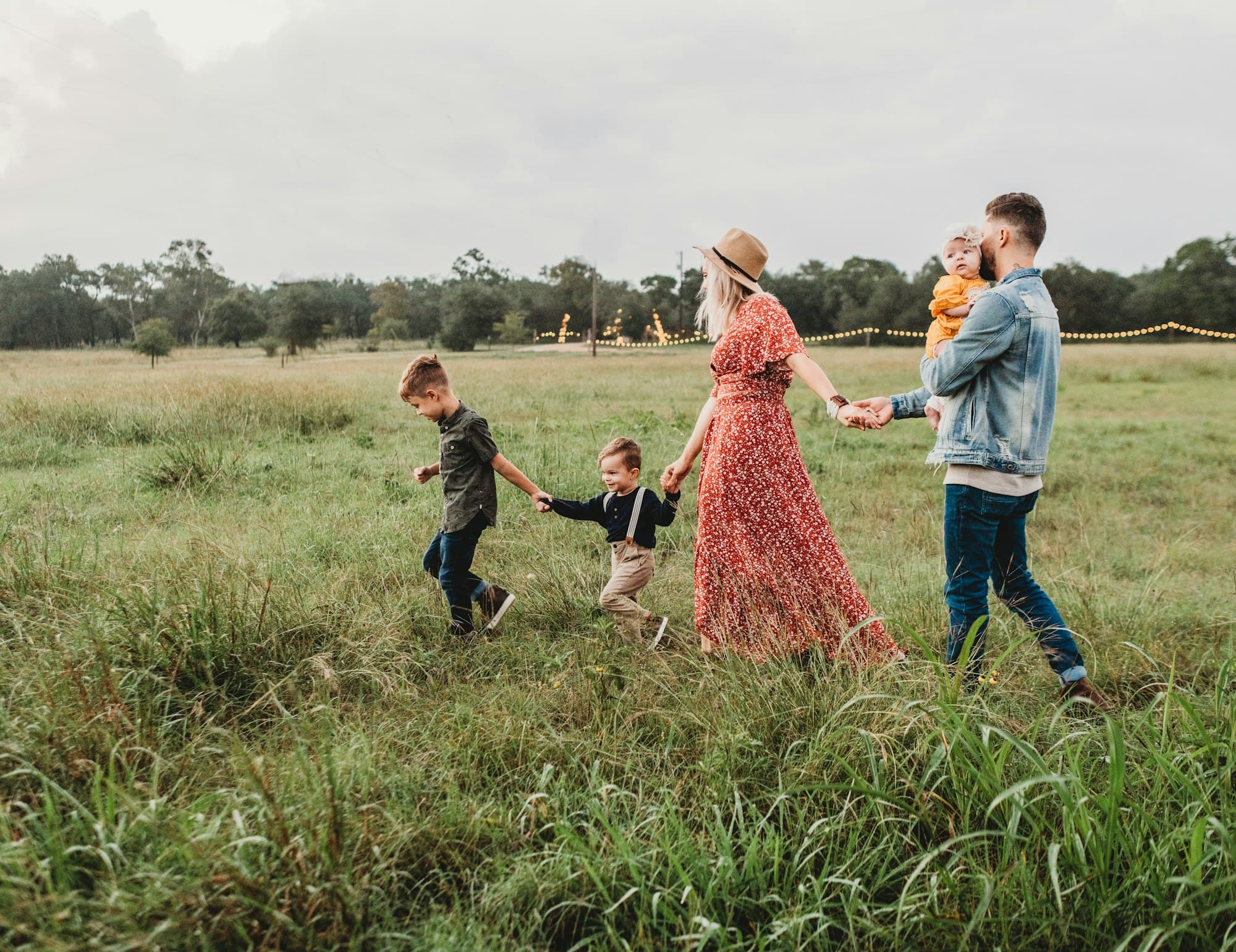 Parents and three young children walking hand in hand through a field