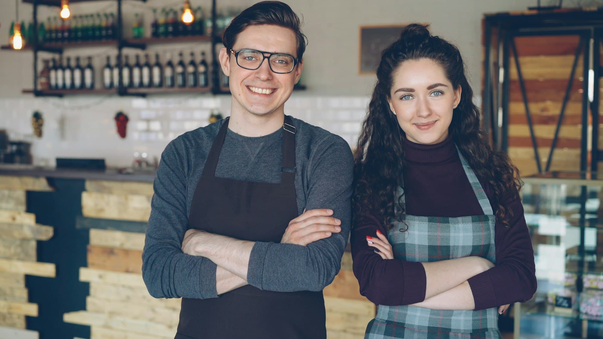 Two smiling cafe owners standing in front of their counter
